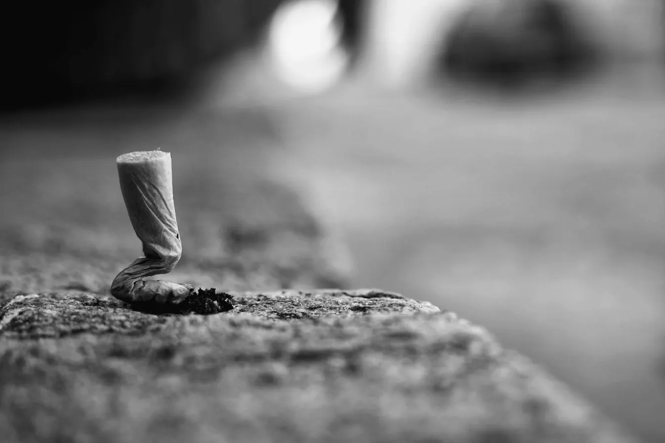 A crushed cigarette butt on a stone ledge